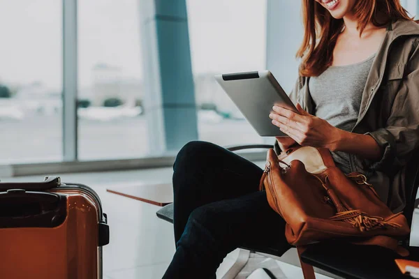 Mulher sorridente está usando tablet no aeroporto — Fotografia de Stock