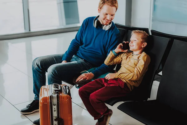 Alegre niño está hablando en el teléfono inteligente sentado con papá — Foto de Stock