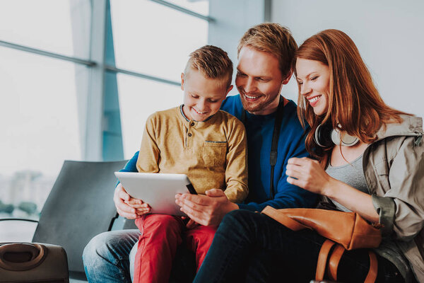 Cheerful family is hanging out with touchpad in lobby