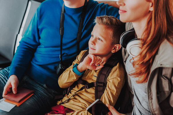 Thoughtful boy is waiting for flight with parents