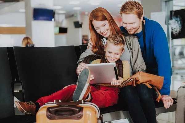 Familia alegre está utilizando el ordenador portátil en la sala del aeropuerto —  Fotos de Stock