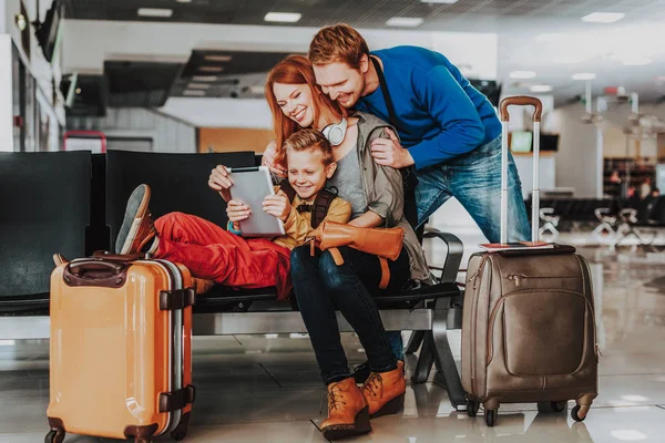 Família alegre está se divertindo com touchpad no aeroporto — Fotografia de Stock