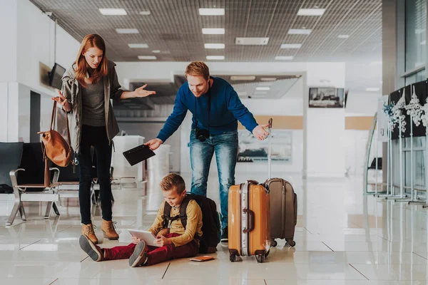 Niño masculino es entretenido con el ordenador portátil antes del vuelo con la familia — Foto de Stock