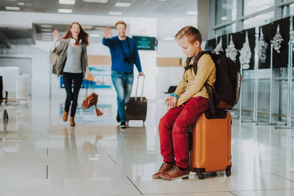 El chico molesto está esperando a sus padres en el aeropuerto. —  Fotos de Stock