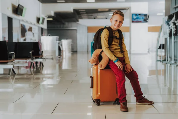 Chico alegre está esperando el vuelo en el aeropuerto — Foto de Stock