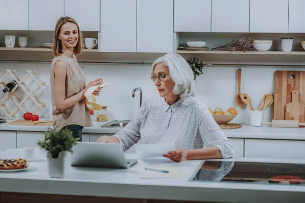 Fröhliche Hündin beobachtet ihre Mutter mit Notizbuch in Küche — Stockfoto