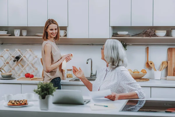 Mujer alegre se está comunicando con mamá en la cocina —  Fotos de Stock