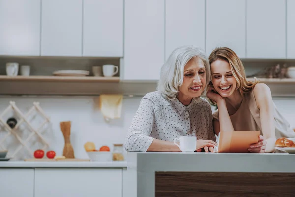 Lykkelig mor med ung dame ser på bilder på kjøkkenet – stockfoto