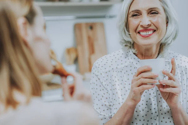 Mujer madura alegre está disfrutando del café en compañía de la familia — Foto de Stock