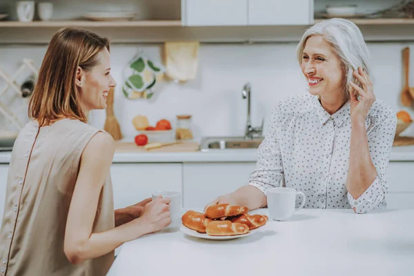 Feliz joven mujer está desayunando con la madre en casa —  Fotos de Stock