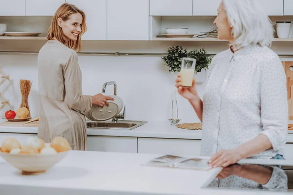 Fröhliches Weibchen spült Geschirr und spricht mit Mutter — Stockfoto