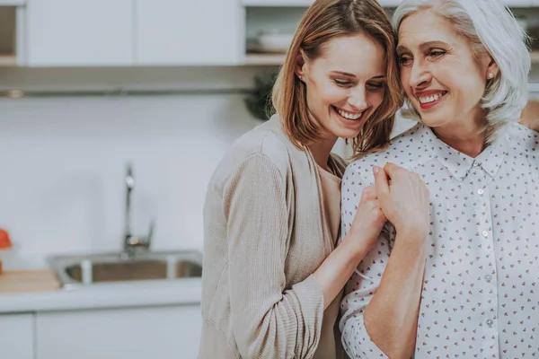 Mujer feliz está abrazando a su madre en la cocina —  Fotos de Stock