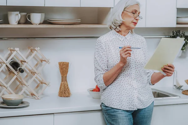 Mujer madura está leyendo receta en la cocina — Foto de Stock