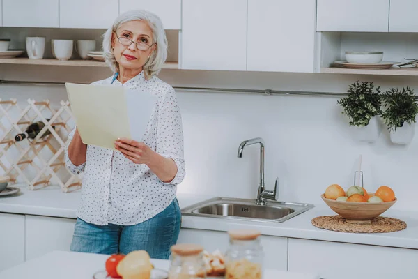 Mujer madura está leyendo receta en la cocina —  Fotos de Stock