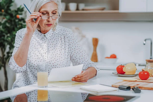 Yaşlı kadın evde yemek yapma hakkında notlar okuma