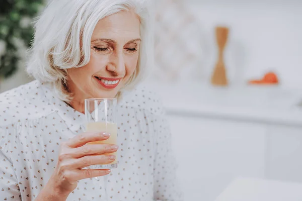 Relajada anciana está bebiendo jugo en casa —  Fotos de Stock