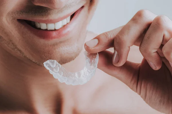 Primer plano del hombre sonriente sosteniendo protector bucal transparente —  Fotos de Stock