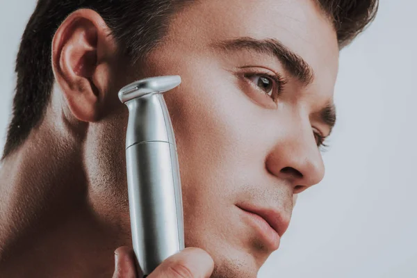 Primer plano del hombre sosteniendo la máquina de afeitar eléctrica y buscando la calma —  Fotos de Stock