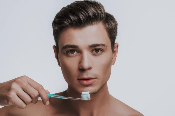 Calma hombre caucásico sosteniendo cepillo de dientes en su mano —  Fotos de Stock