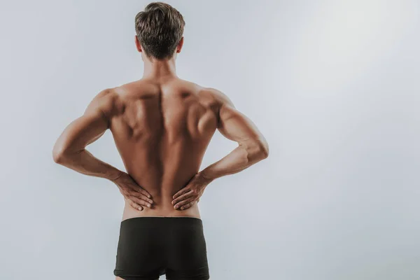 Waist up of muscular man putting hands on the back — Stock Photo, Image