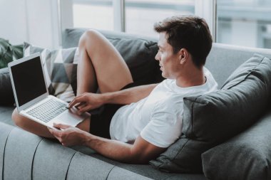 Adam kanepede yatan ve modern dizüstü kullanarak iç çamaşırı