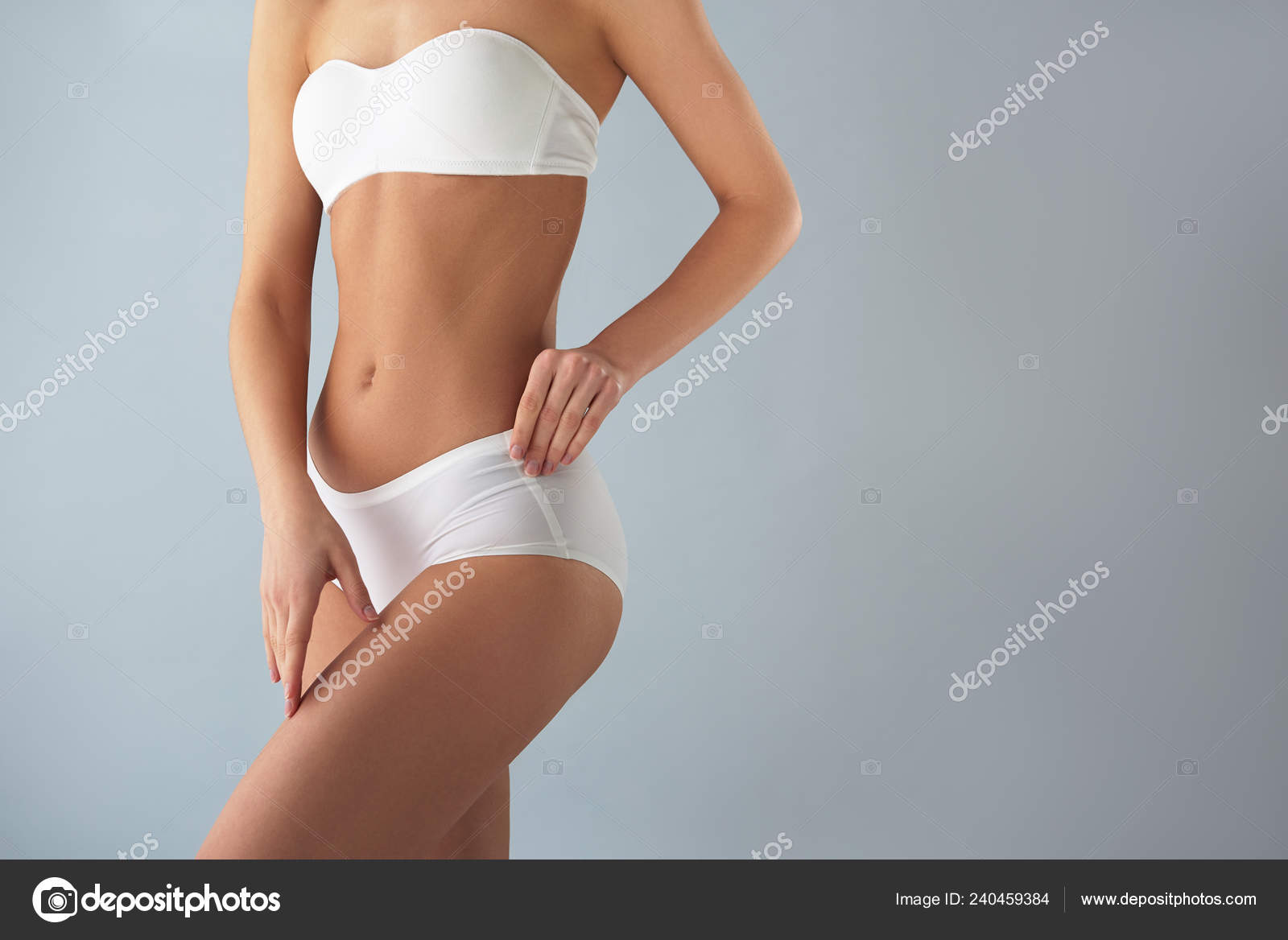 Young woman in white lingerie standing against light blue