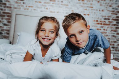 Kız ve erkek kardeşim yatakta birlikte döşeme gülümseyen