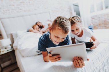 İki çocuk yatakta döşeme ve dijital tablet bak