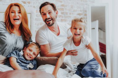 Mutlu aile yatakta kamerada poz gülüyor
