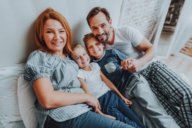 Aile yatağa birlikte sabah döşeme gülümseyen