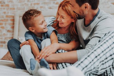 Aile yatakta birlikte gülümseyen mutlu sabah