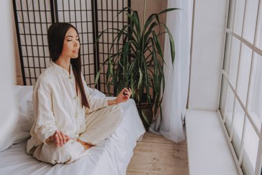 Evde yatakta meditasyon sakin Asyalı kadın