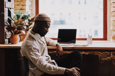 Sakin Afro-Amerikan adam düşünceli tek başına otururken bakıyor