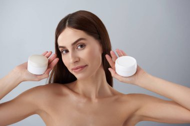 Çıplak omuz kozmetik ürünleri tutan güzel genç bir bayanla