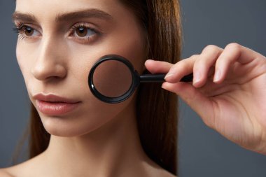 Büyüteç aracılığıyla mükemmel cilt gösteren güzel kız
