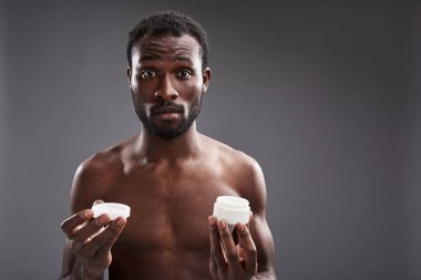 Sürpriz bir afro Amerikalı adam krem kavanoz holding kadar bel