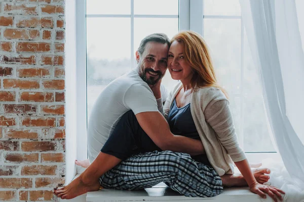 Echtpaar dat teder knuffelen op de vensterbank — Stockfoto