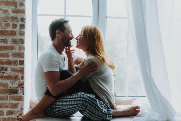 Älskade par ömt kramar på fönsterbrädan — Stockfoto