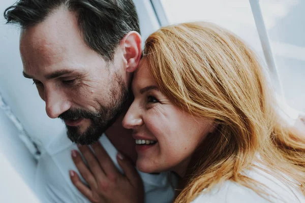 Happy romantic couple tenderly embracing near window