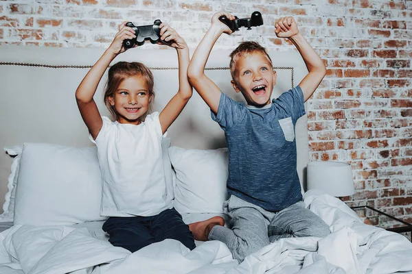 Menino e menina feliz jogando com console de jogo — Fotografia de Stock