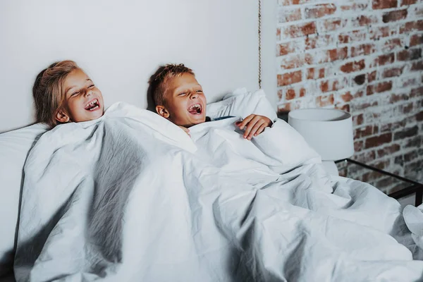 Två glada barn titta på roliga program hemma — Stockfoto