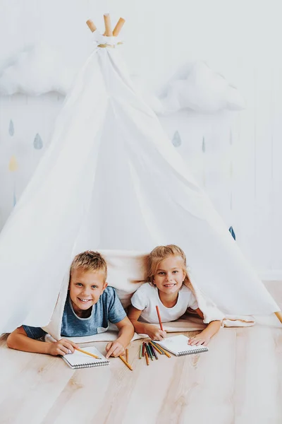 Två söta barn rita tillsammans i wigwam — Stockfoto