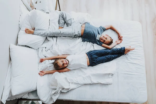 Alegre hermano y hermana acostado en la cama y divertirse —  Fotos de Stock