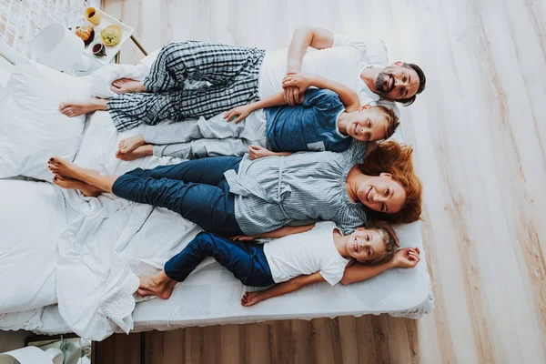 Glada föräldrar med sina barn som lägger på säng — Stockfoto
