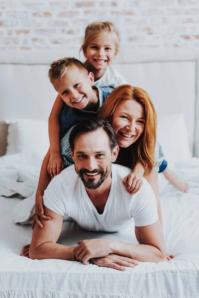 Glimlachende man en vrouw op bed te leggen met kinderen — Stockfoto