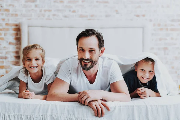 Lachende ouder en twee kinderen tot op bed — Stockfoto