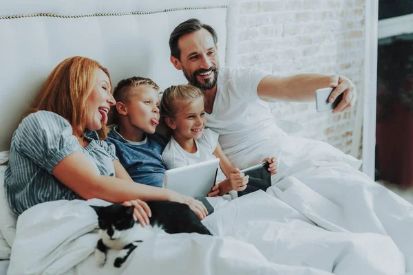 Οικογένεια κάνοντας αστεία selfie μαζί στο κρεβάτι — Φωτογραφία Αρχείου