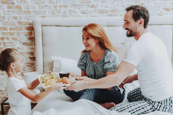 Gelukkig meisje ontbijt om ouders in bed — Stockfoto