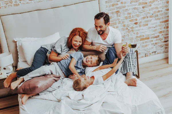 Familia feliz riendo mientras juegan juntos en la cama —  Fotos de Stock