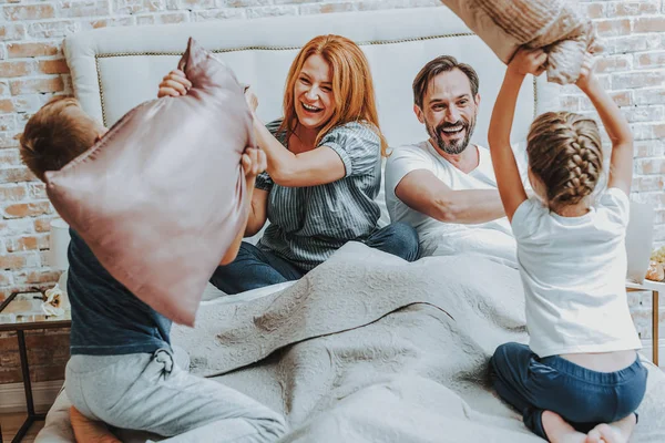 Familia feliz luchando por la almohada juntos en la cama —  Fotos de Stock